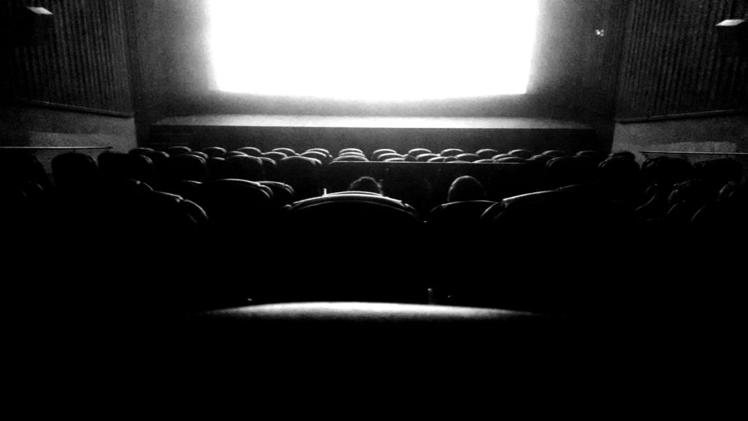 A black-and-white photo of a movie theatre during a film.