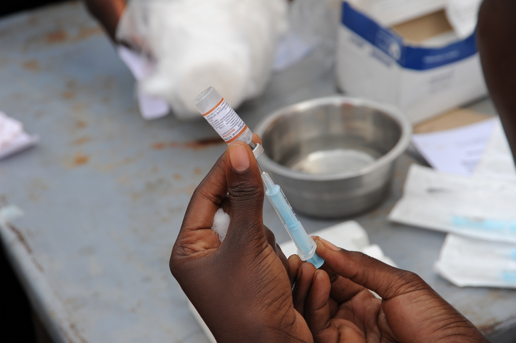 A photo of a person withdrawing medicine from a vial with a syringe