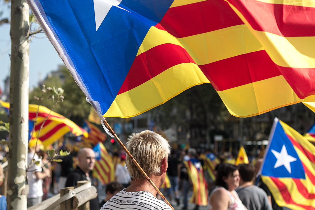 A photo of a man holding a Catalan independence flag.