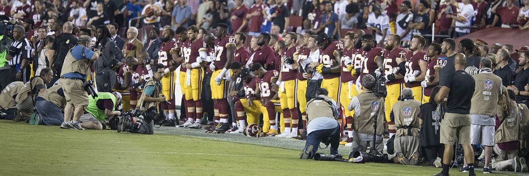 A photo of football players taking a knee during the National Anthem.
