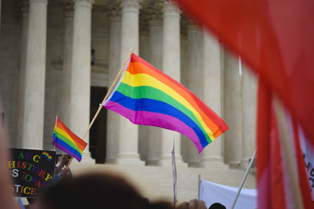 A photo of a rainbow flag being waved outside the U.S. Supreme Court.