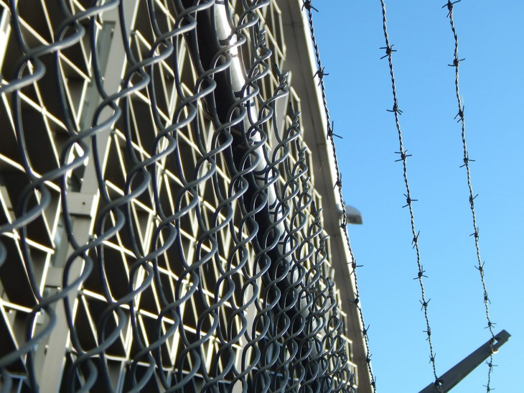 A low-angle photo of barbed wire at a prison.