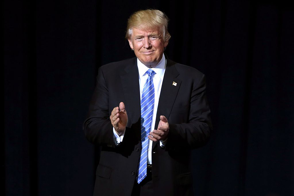 A dark photo of Donald Trump clapping.