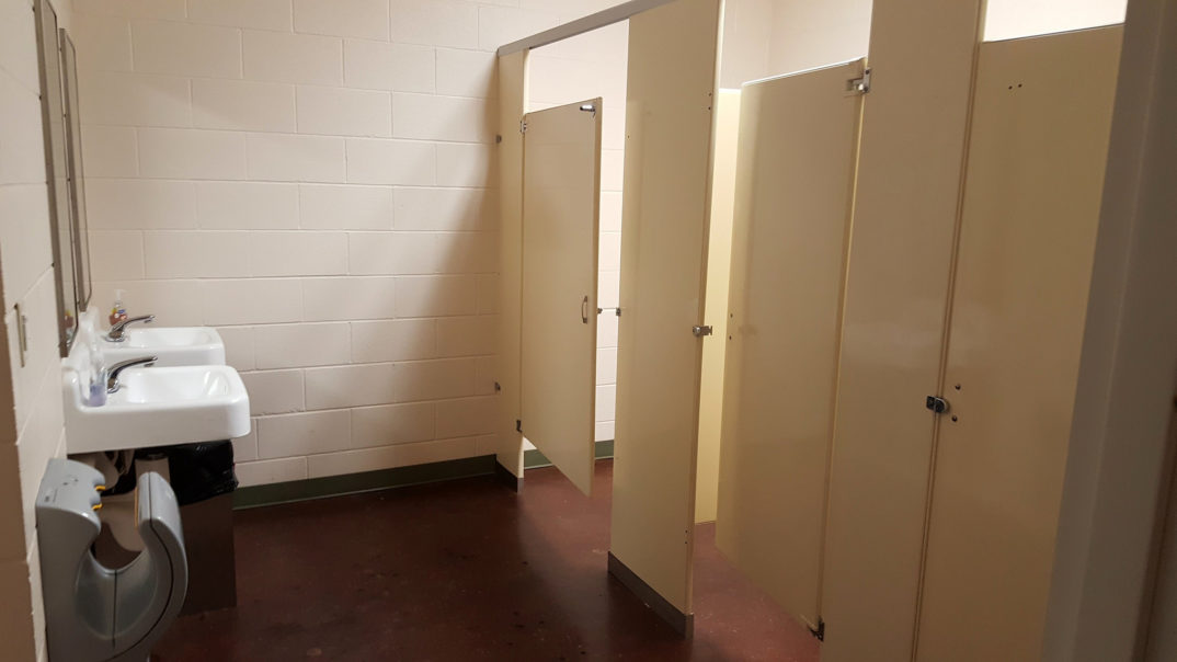 An image of three bathroom stalls, with one stall door open.