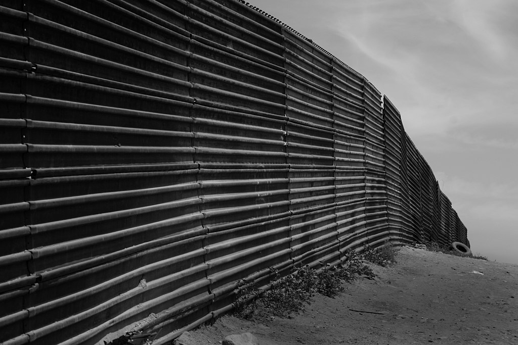 A black-and-white image of the U.S.-Mexico border wall fence.