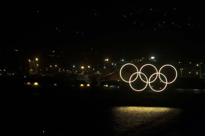 Photo of illuminated Olympic rings against dark city