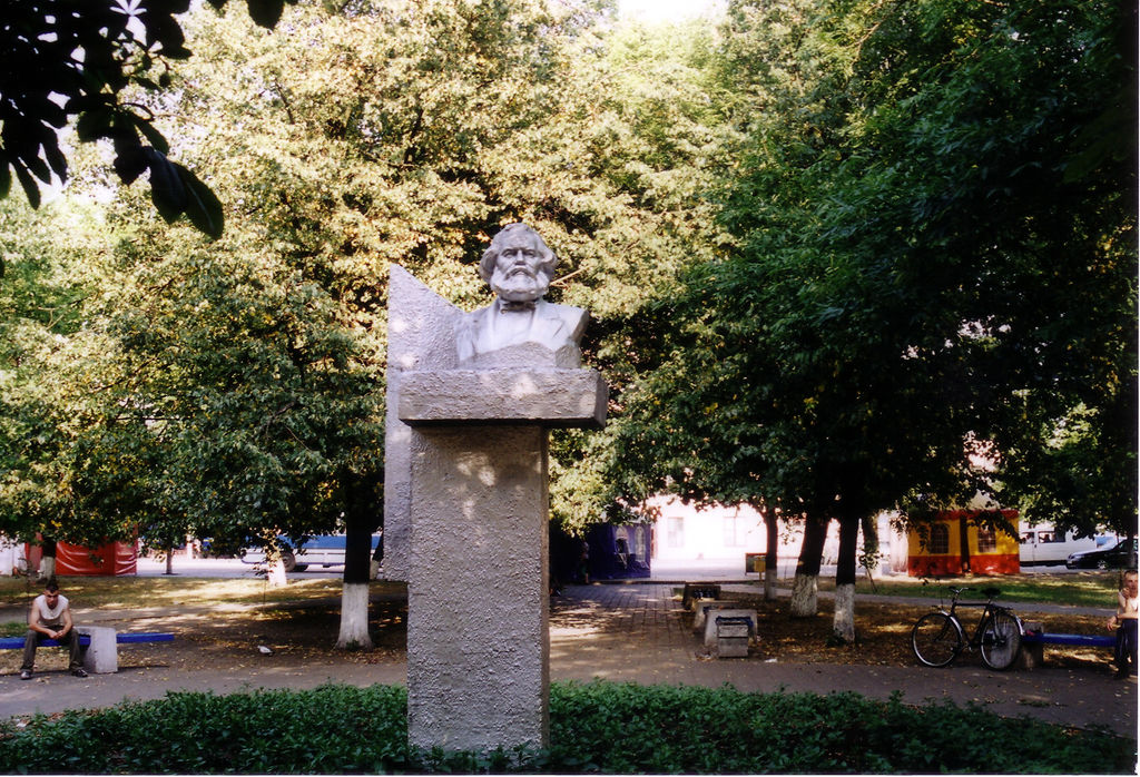 Photo of Karl Marx bust on a plinth in a small park