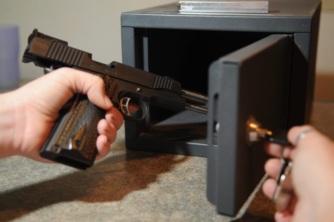 Image of a person putting a handgun into a gun safe.