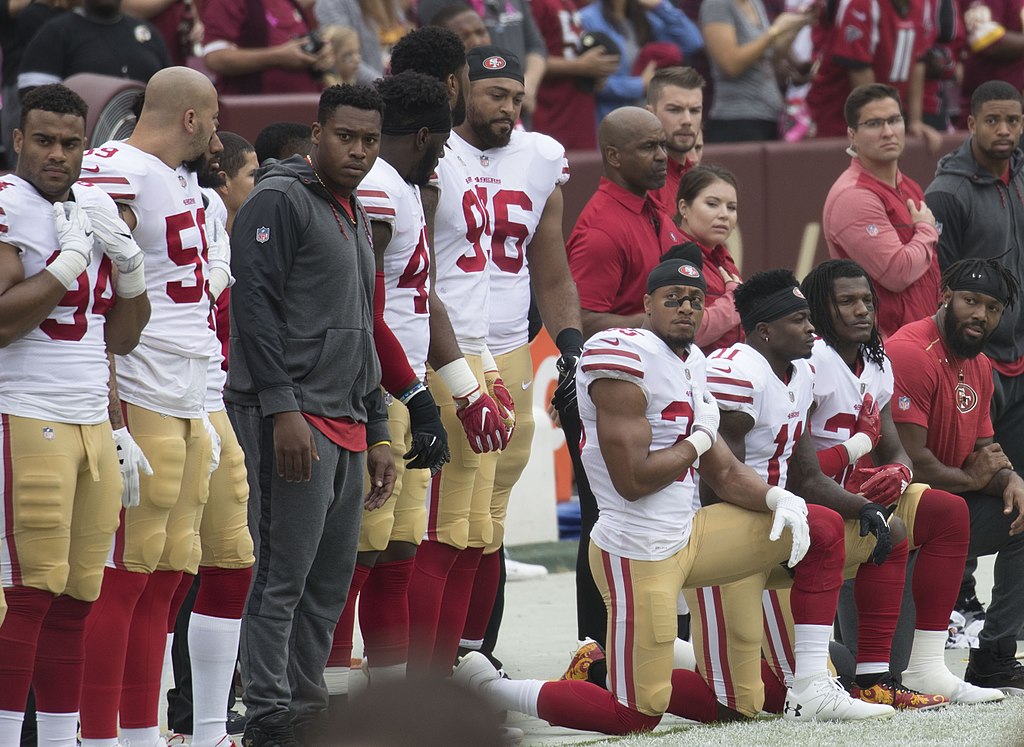Photo of San Francisco 49ers players kneeling during the National Anthem.