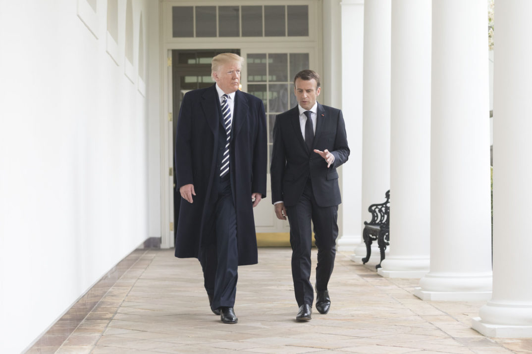 Photograph of President Trump and President Macron walking outside the White House, Macron speaking and gesturing with his hand