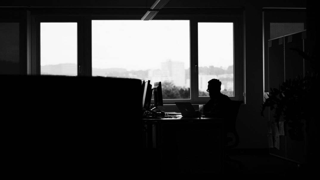 Image of a man alone in a dark computer room