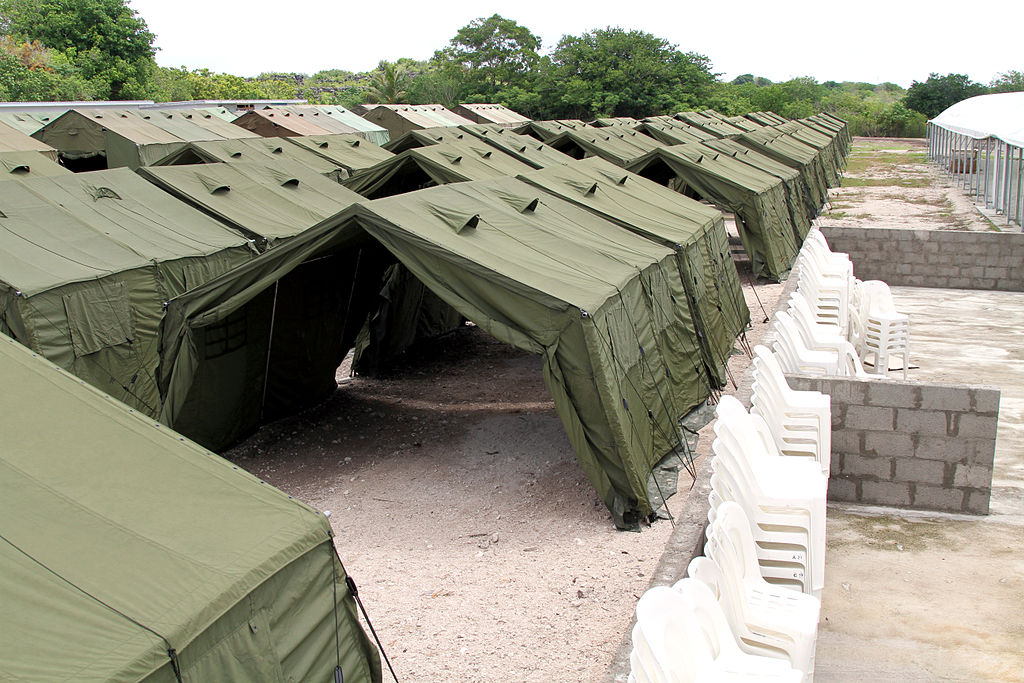 Photograph of a long row of dark green tents