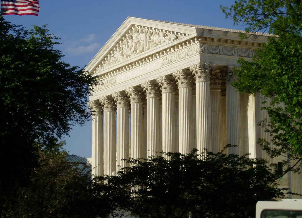 Photograph of the US Supreme Court framed by shrubbery