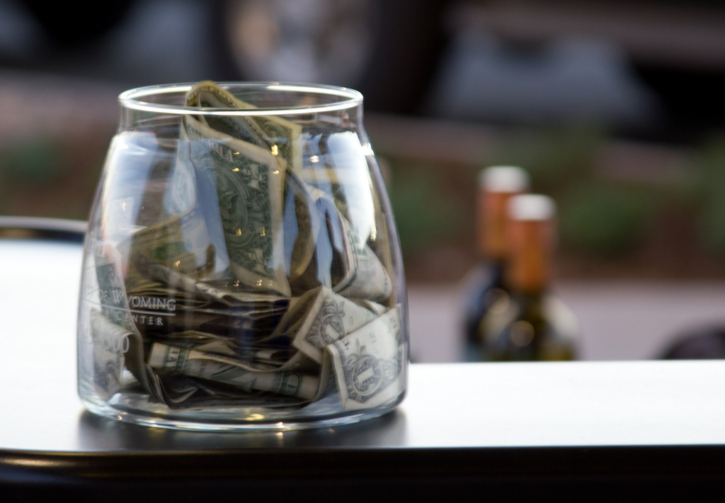 Photograph of a clear glass jar with dollars in it