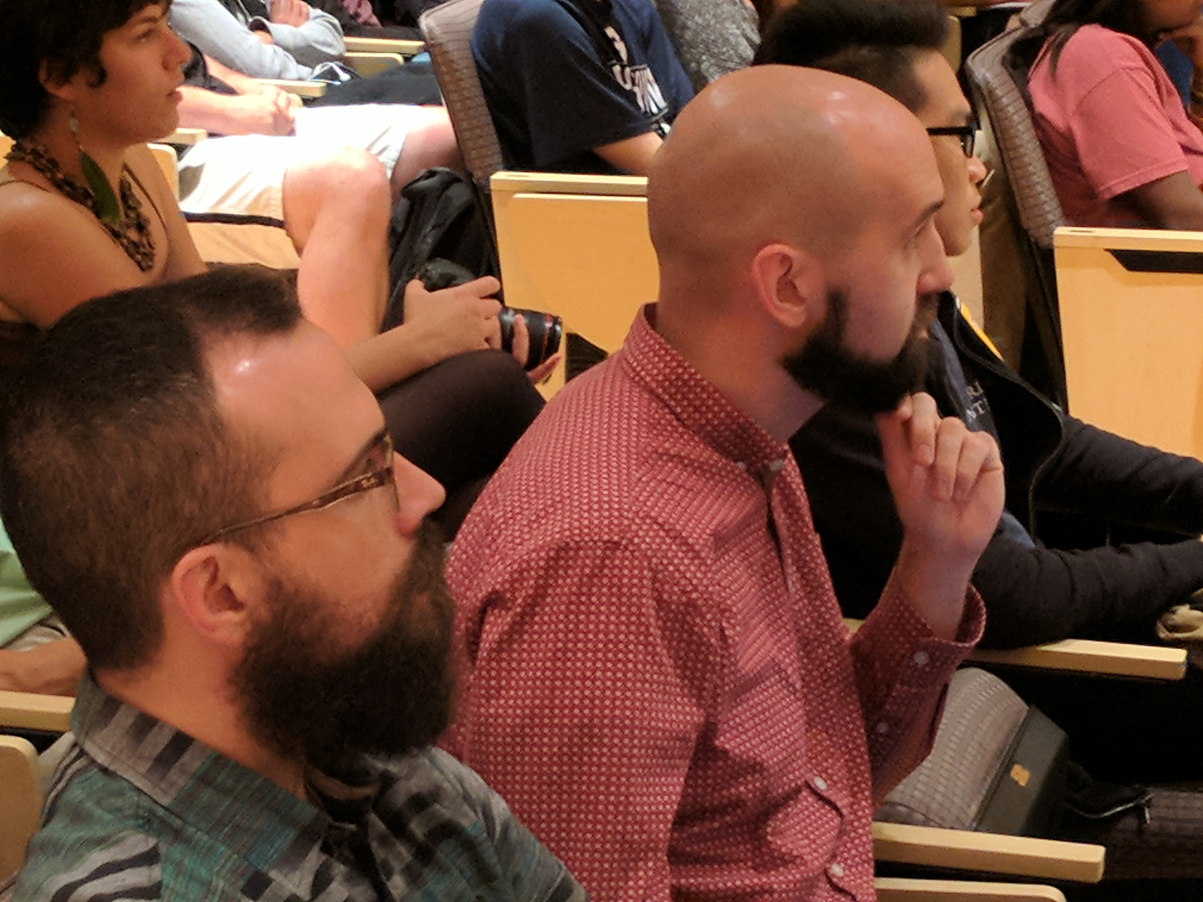 Group of people sitting in an auditorium listening to a speaker out of frame.