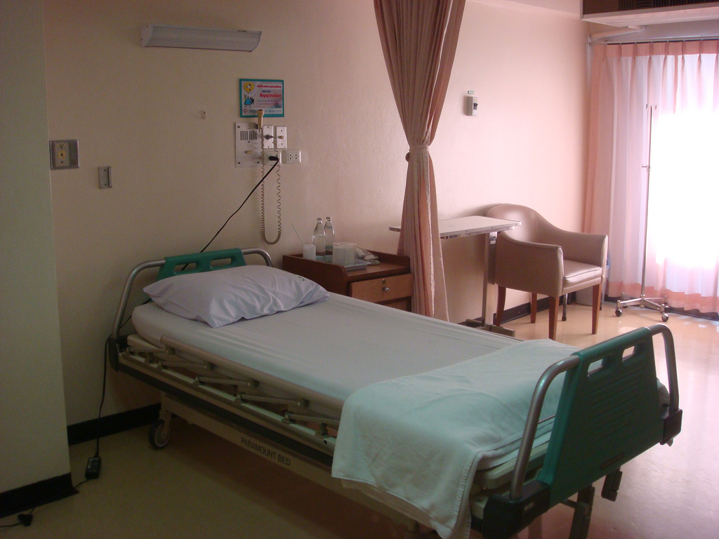 Photograph of a single bed with a curtain and chair