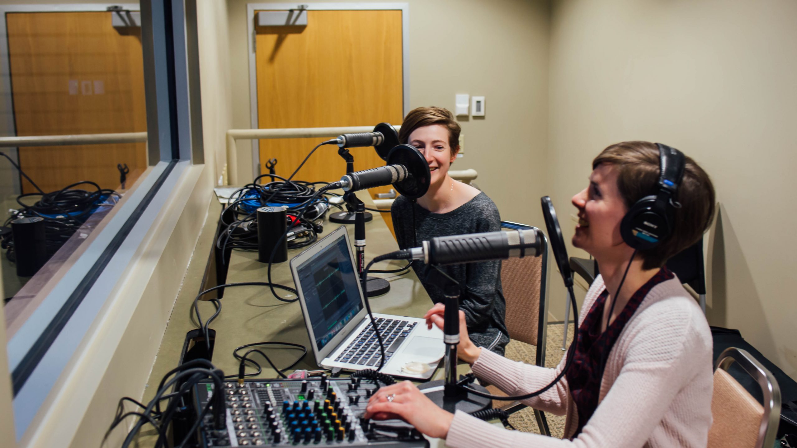 Examining Ethics producers sit behind microphones in a recording booth