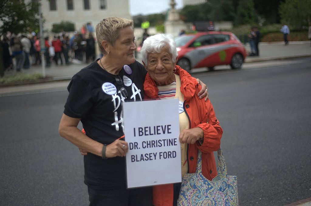 Two women holding a sign that says "I believe Dr. Christine Blasey Ford"