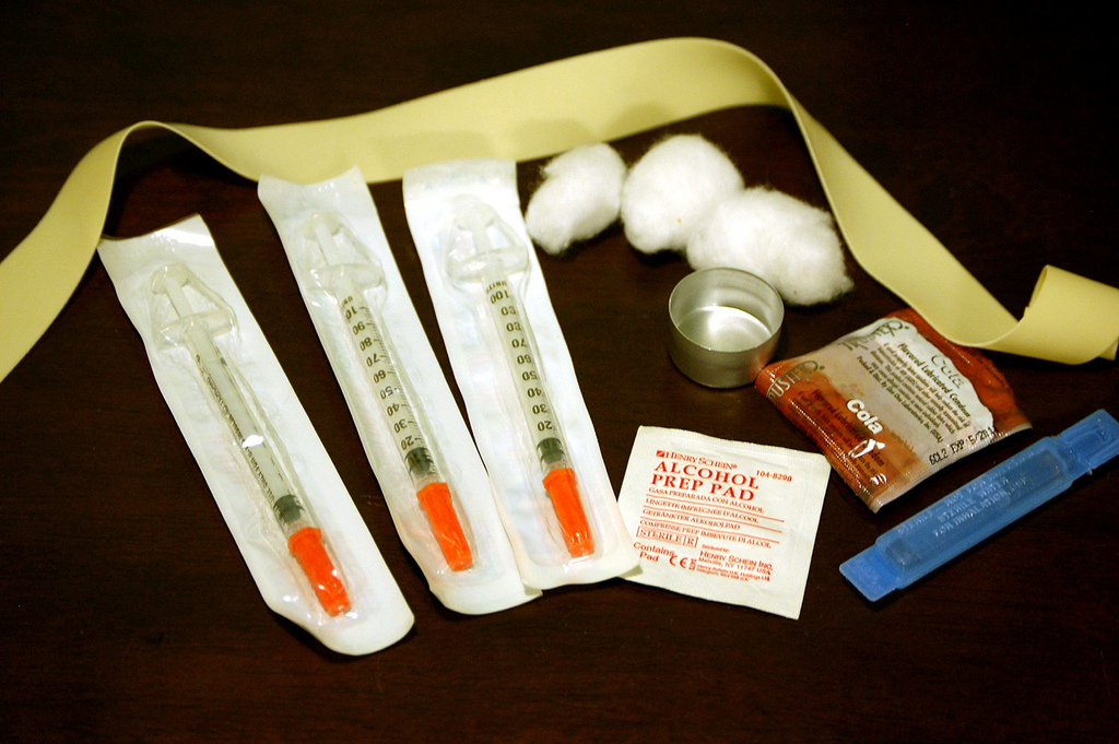 Photograph of a kit for needle exchange, including three needles, cotton pads, and alcohol wipes