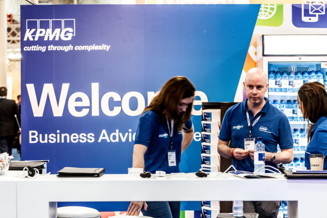 Photograph of people at a booth in front of a partially obscured sign that says "Welcome Business Advisors"