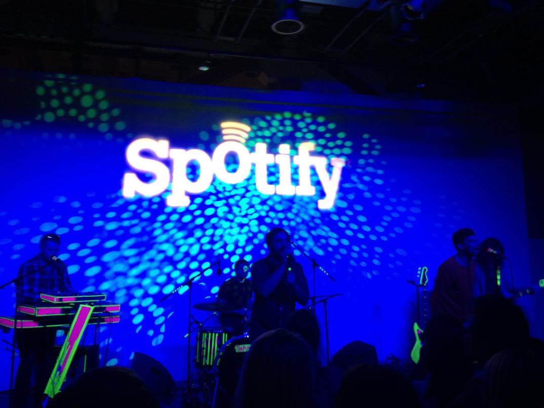 Photo of the Spotify logo behind a band on a stage