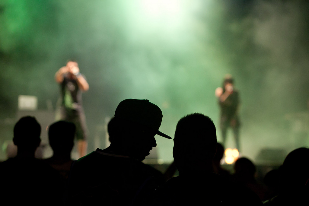 Photograph of an out-of-focus stage and the silhouettes of audience members