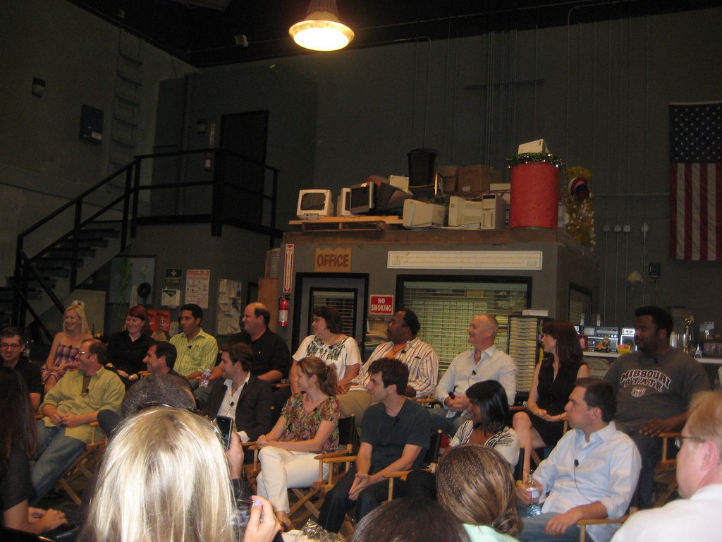 Photograph of the cast of the TV show The Office all sitting for a press conference on set
