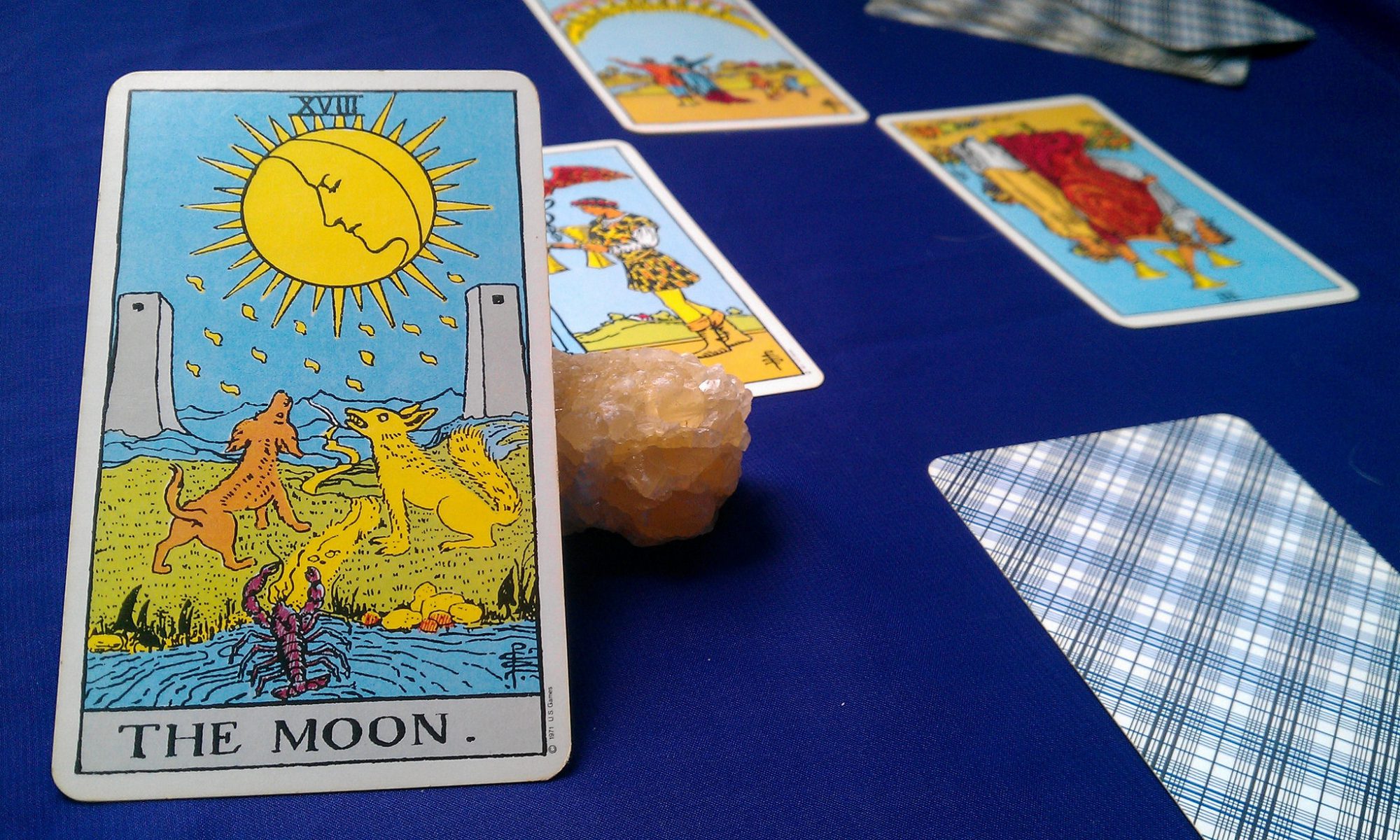 Photograph of the Moon tarot card propped against a crystal with several other tarot cards arranged in the background