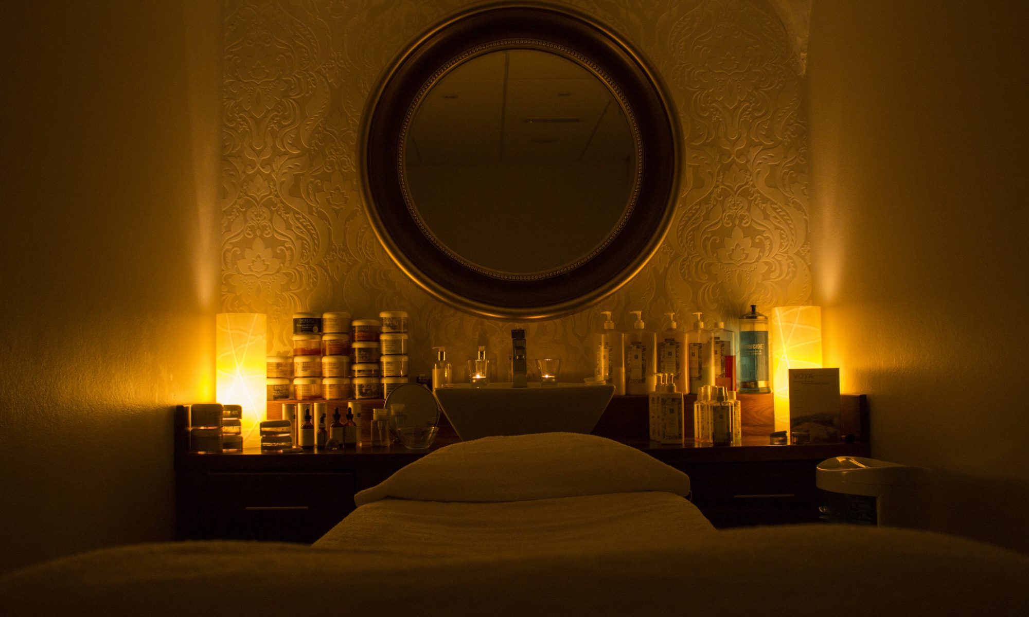 Photo of a lowlit room with candles and a mirror and a bed