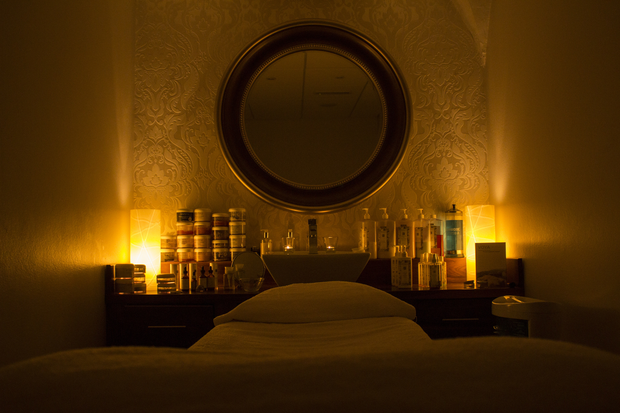 Photo of a lowlit room with candles and a mirror and a bed