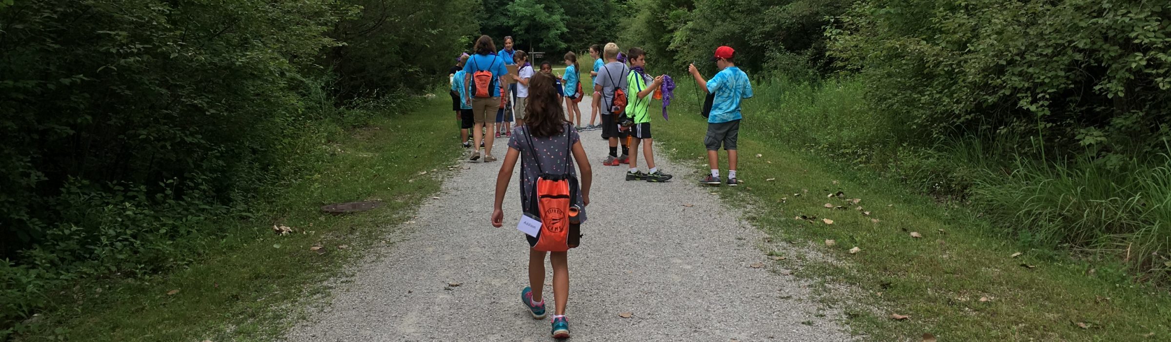 A group of campers exploring the green-treed Nature Park.