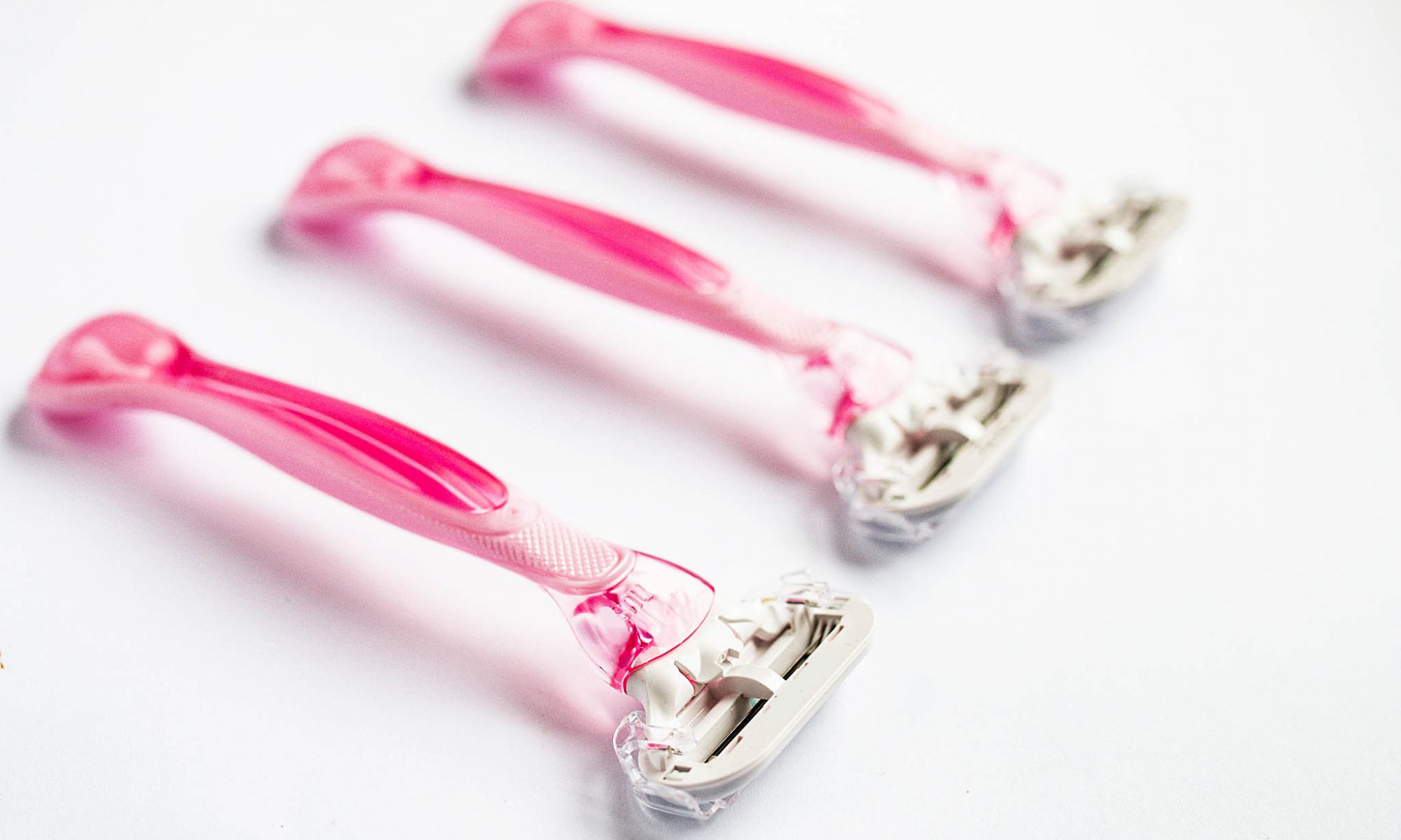 Photo of three pink razors in a diagonal line on a white background