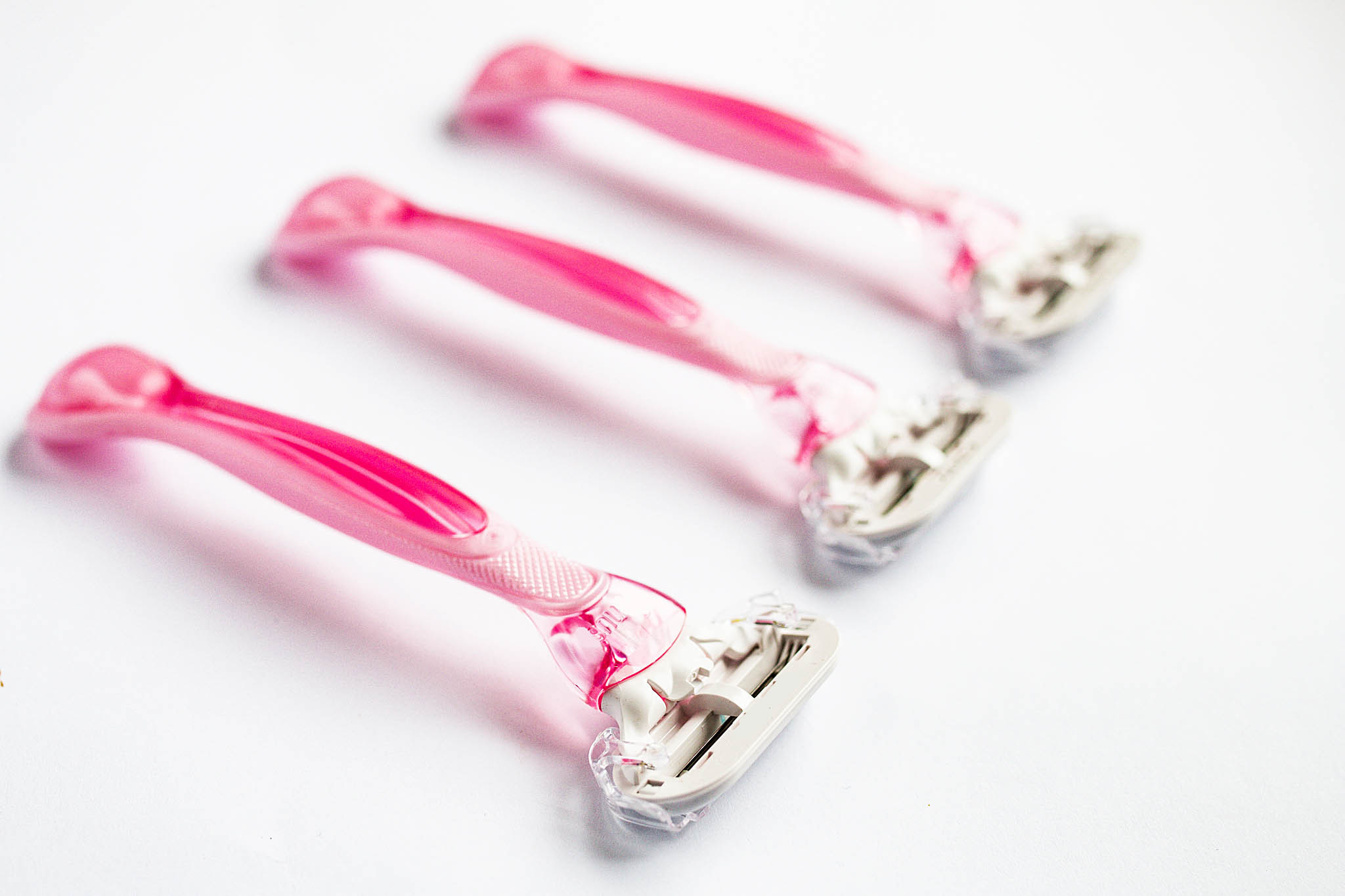 Photo of three pink razors in a diagonal line on a white background