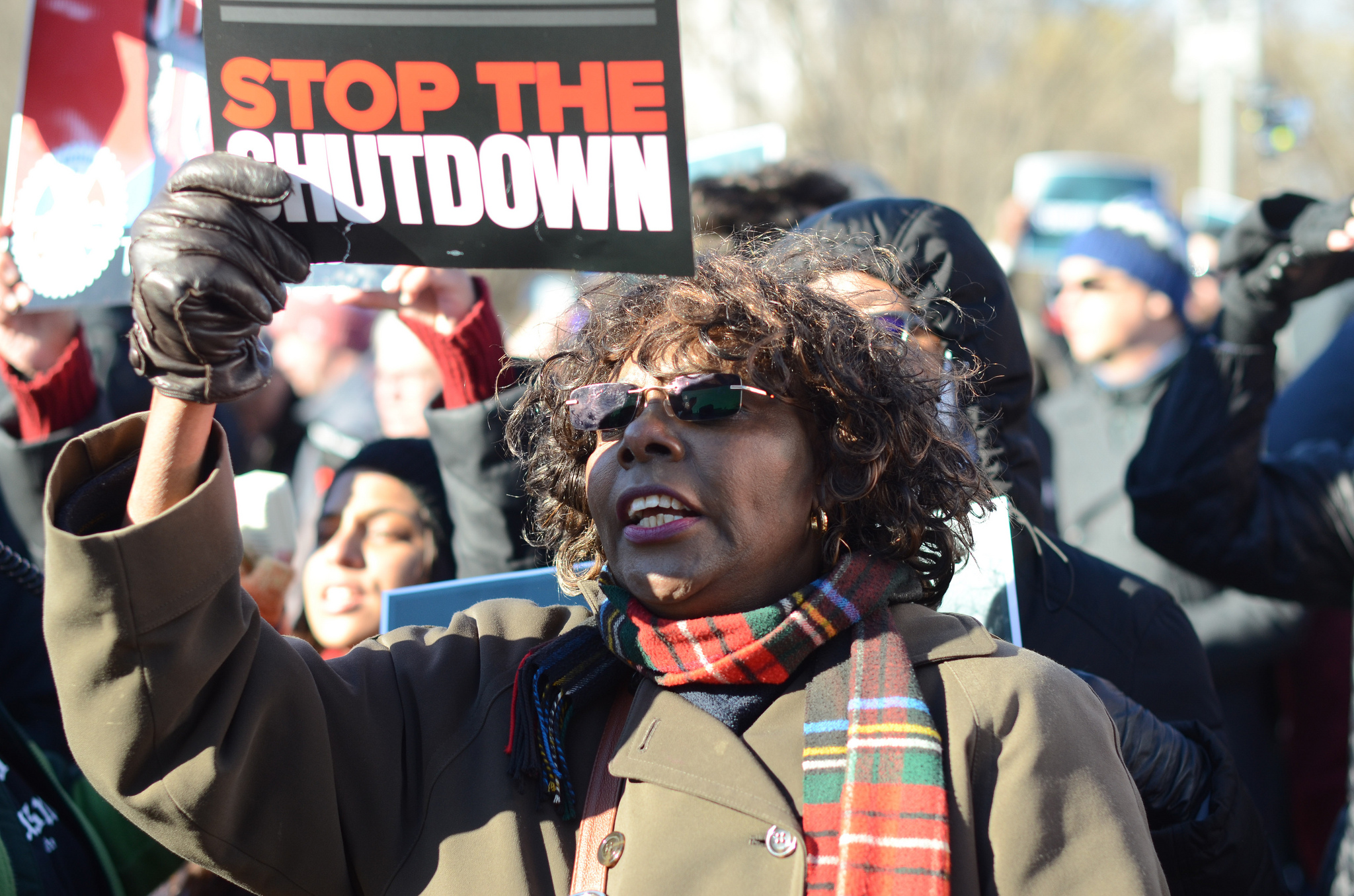 A woman holding a sign that says "stop the shutdown"