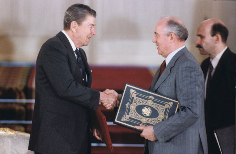 Photograph of Reagan and Gorbachev shaking hands and holding a document