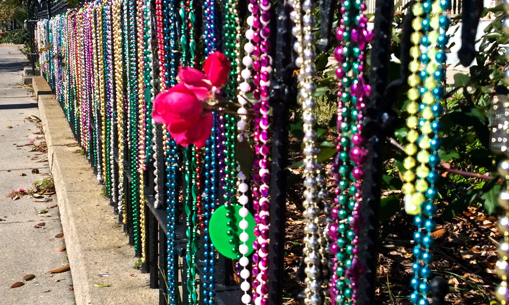 A fence covered in Mardi Gras beads of various colors