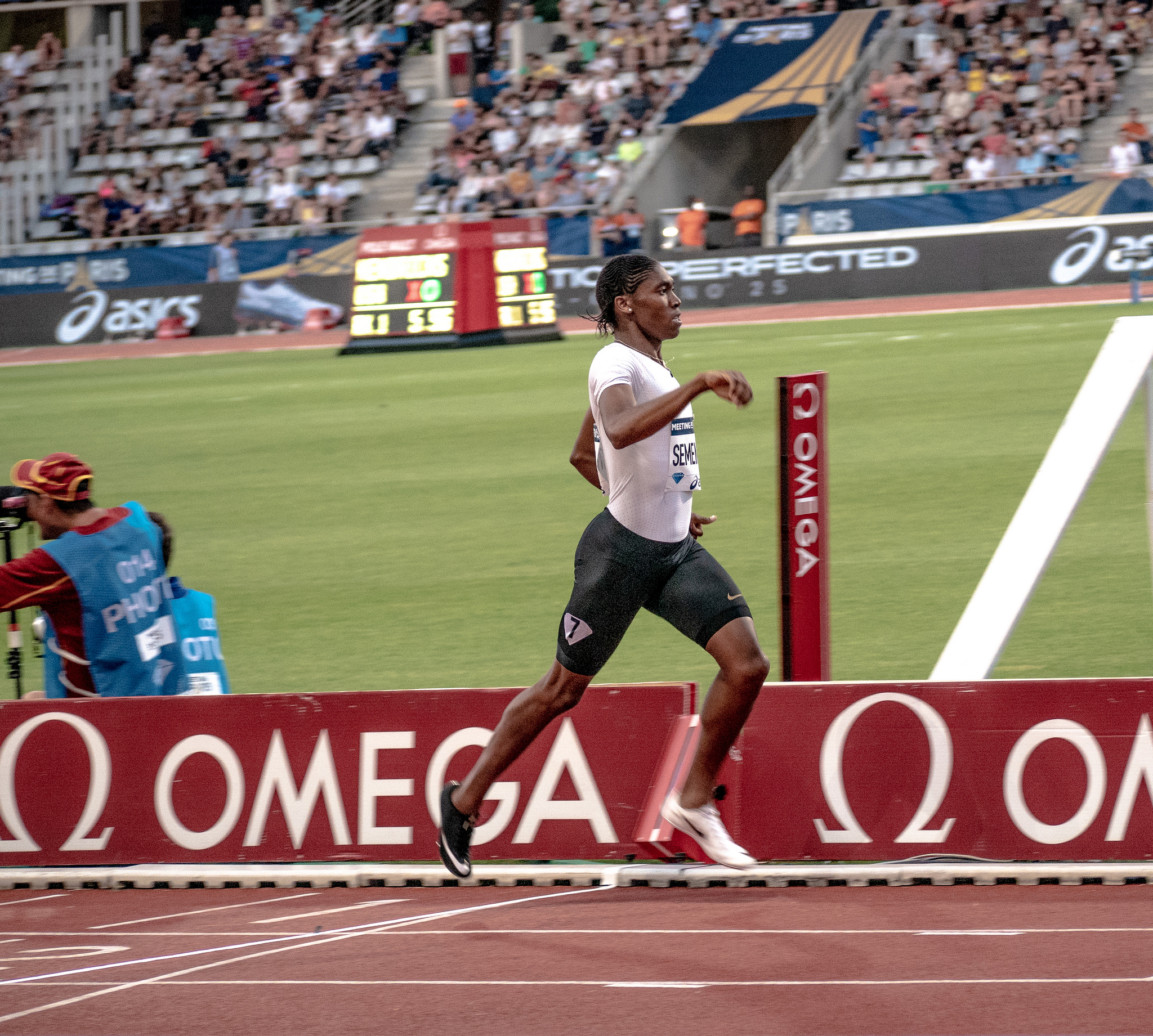 Runner Caster Semenya running across a finish line on a track in a stadium