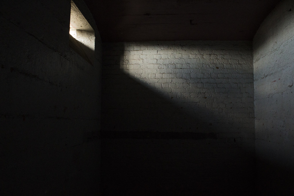 photograph of dark empty cell with small slit of sunshine