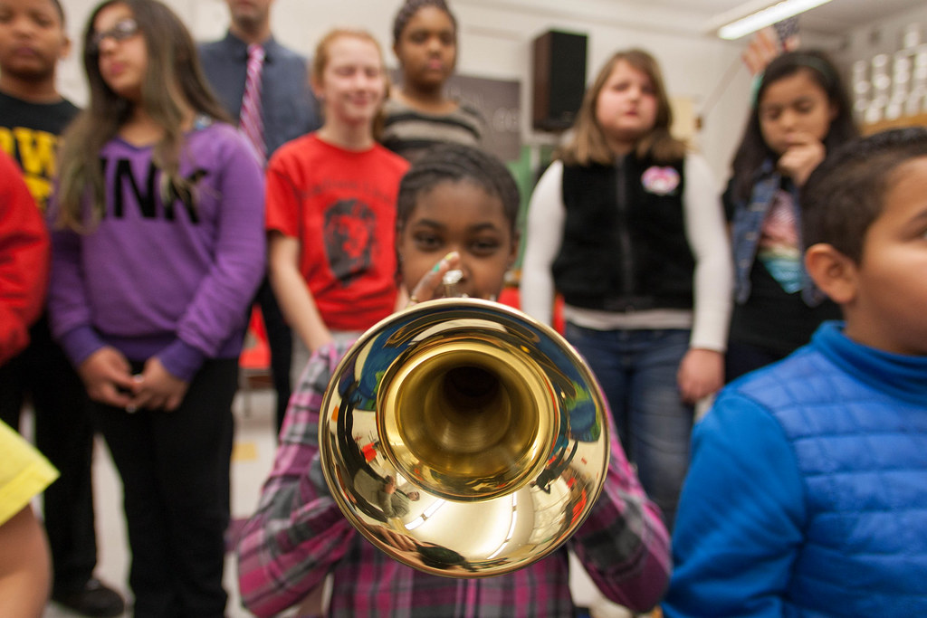 photograph of a girl playing the trumpet in a group of young students