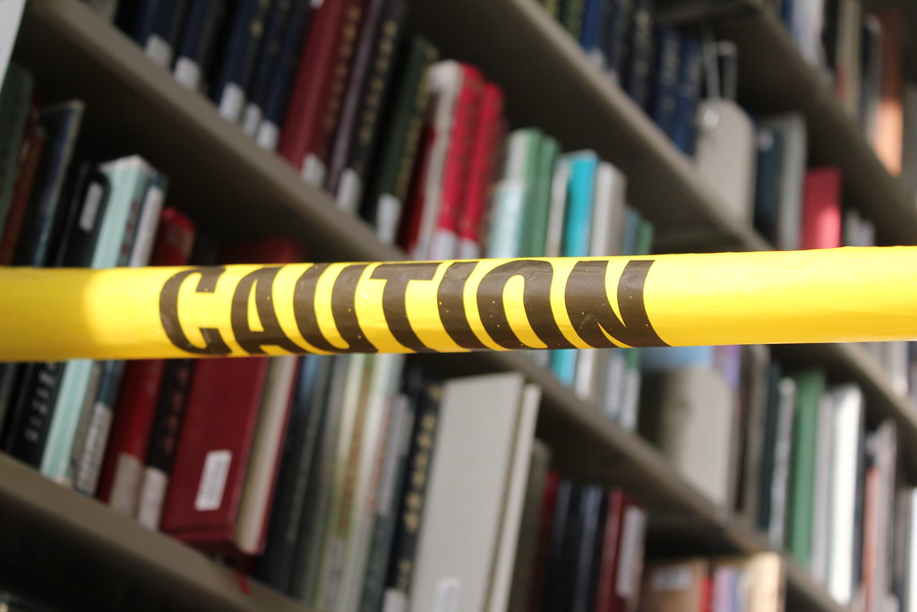 photograph of caution tape around library book shelves