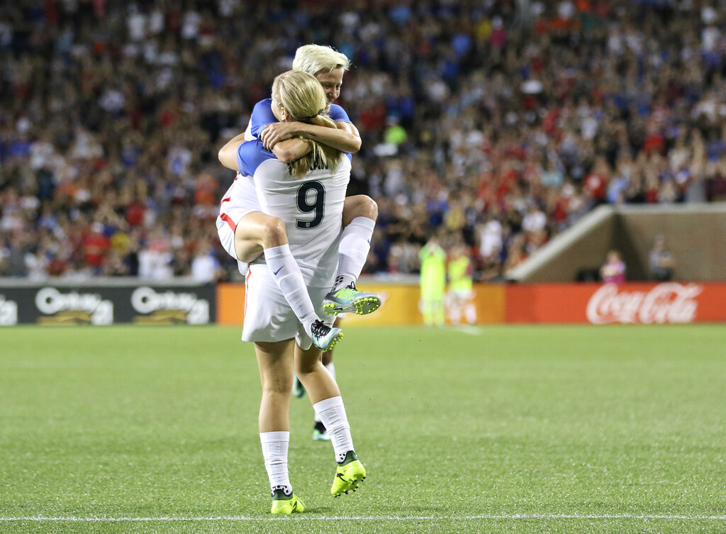 photograph of two female soccer plays celebrating during match