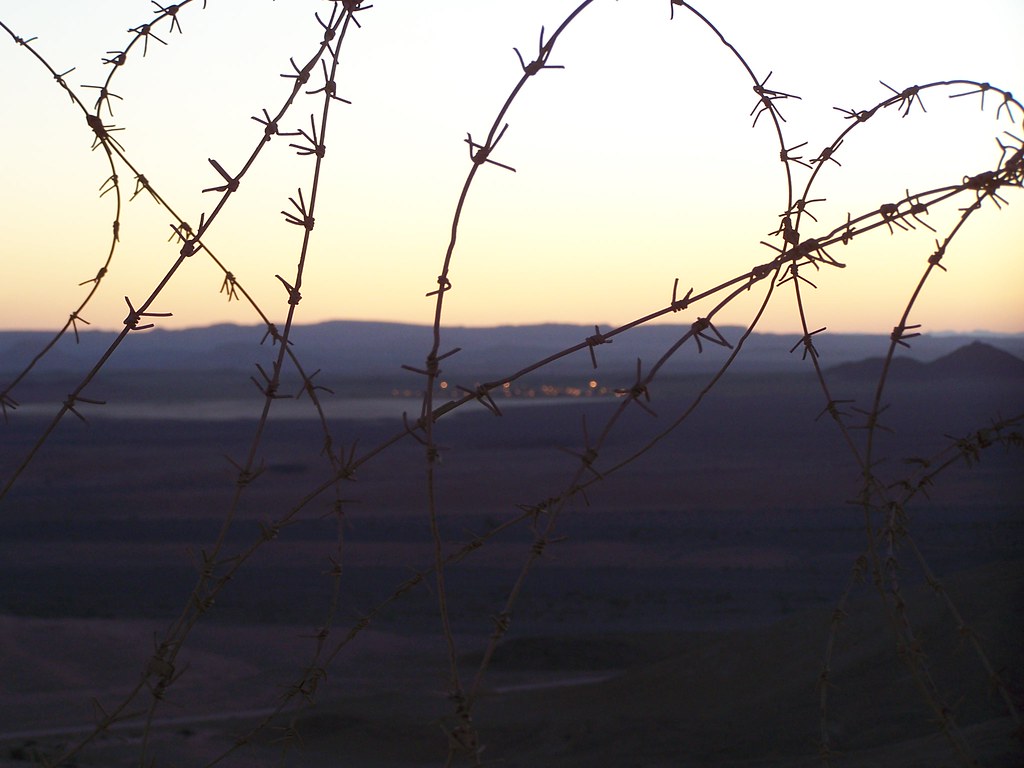 photograph of barbed wire fence with camp in the distance