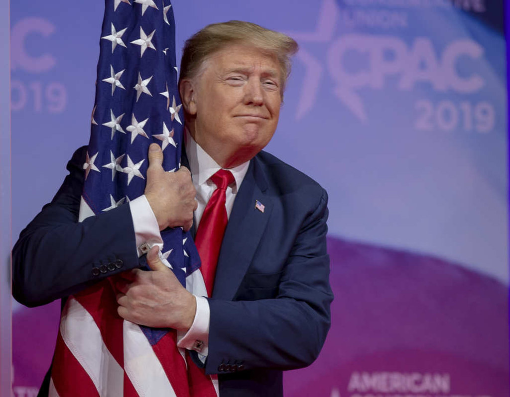 photograph of Trump hugging flag on stage