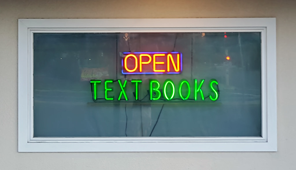 photograph of neon "Open" and "Textbooks" signs in window