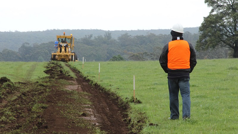 photograph of road construction beginning with trees in distance