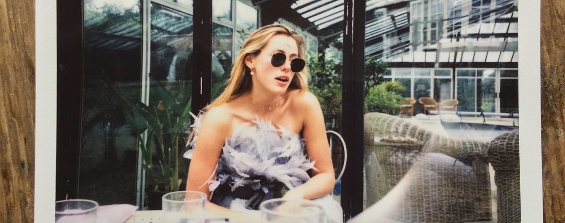 Polaroid picture of a young woman with yellow hair and sunglasses