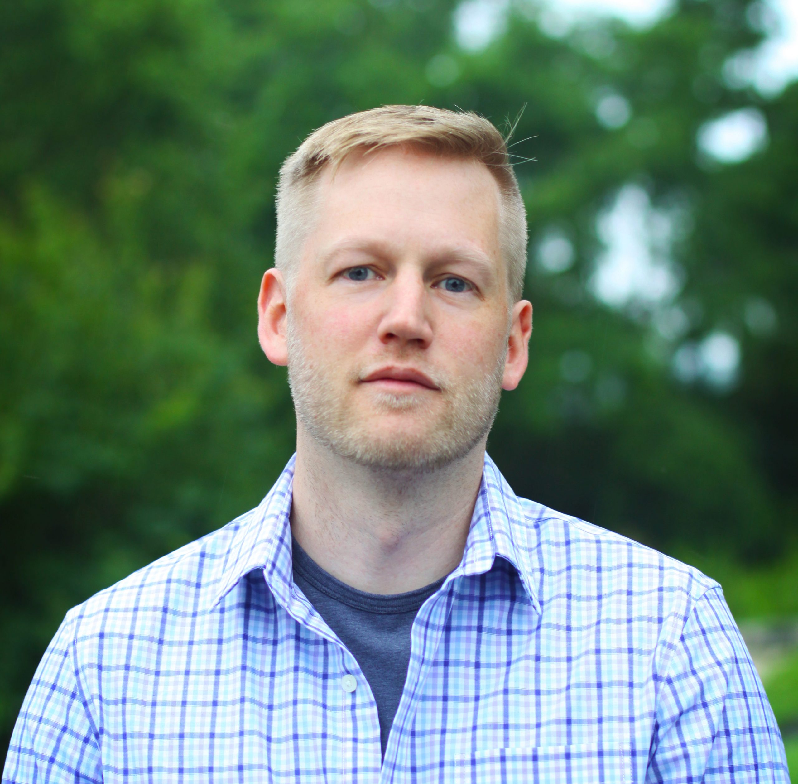 Color photograph of a man in front of a bunch of trees