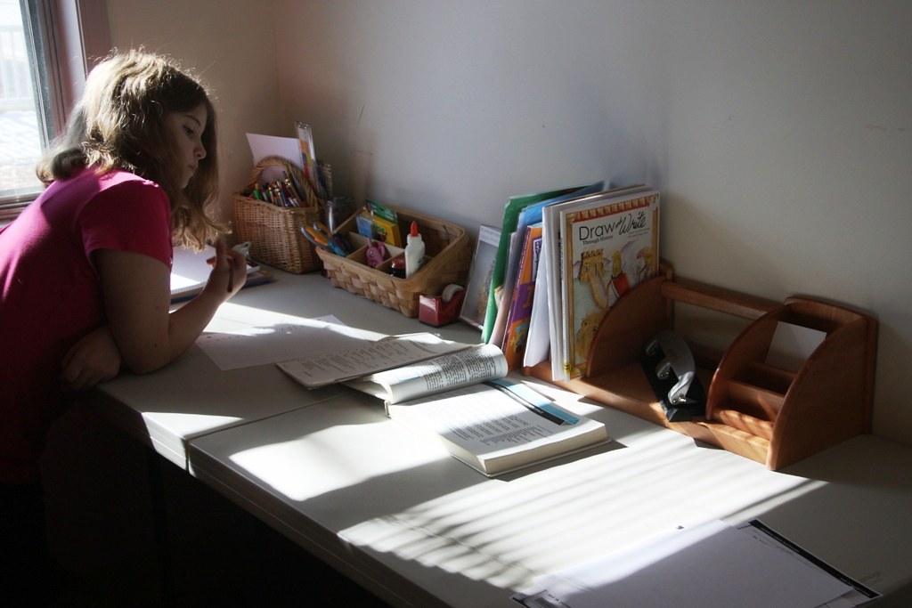 photograph of young girl doing school work in room
