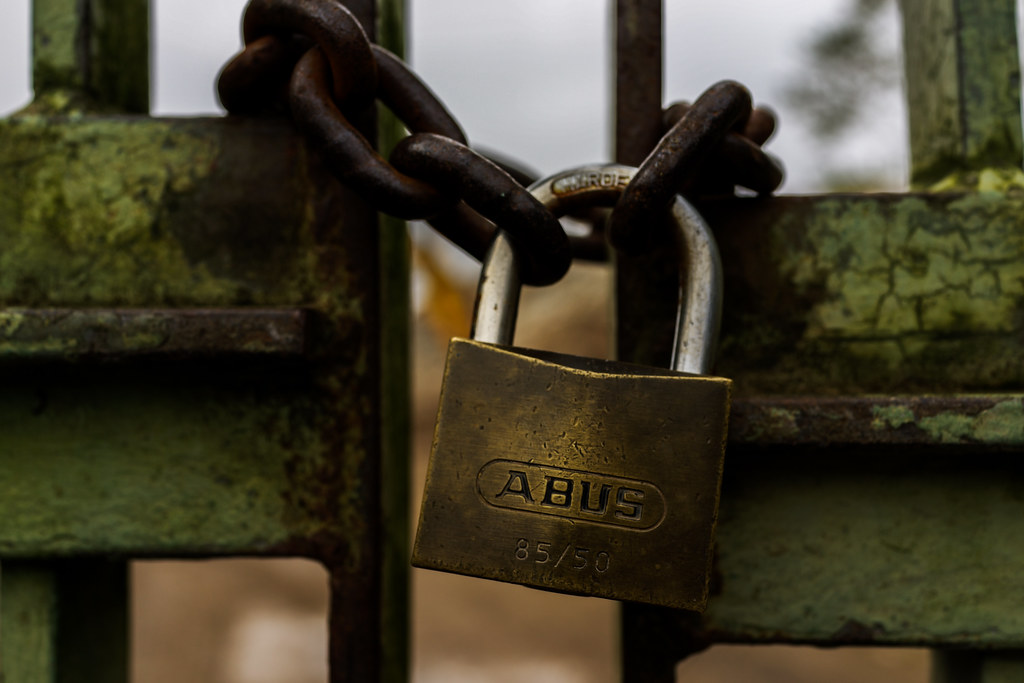 cloeup photograph of lock on gate with iron chain