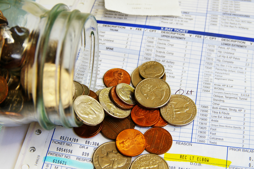 photograph of coin jar spilling out on top of medical bills